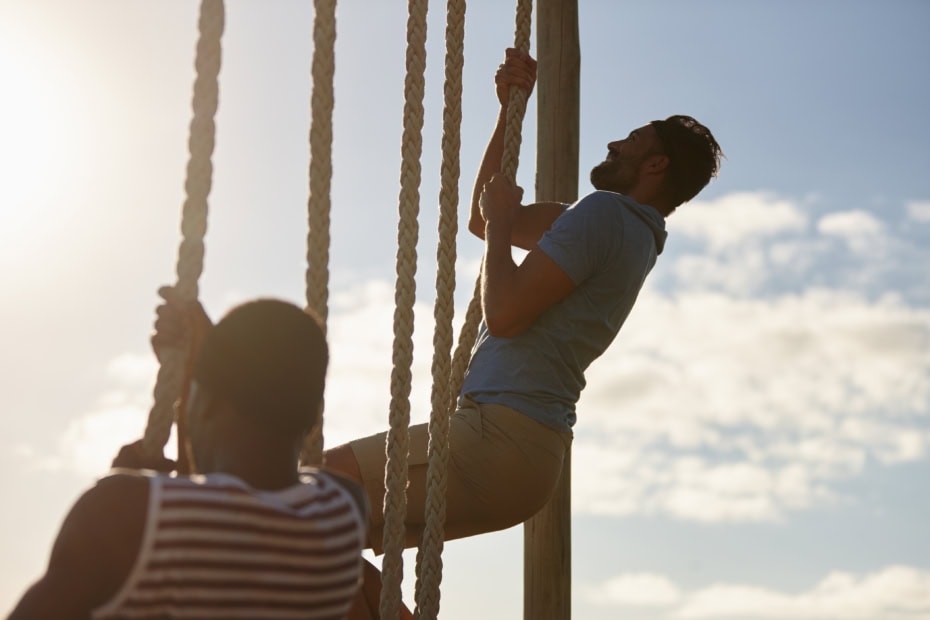 Two young men climbing up ropes